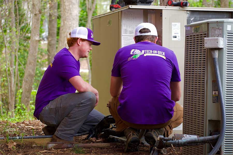 Tech-On-Deck technician repairing outdoor AC unit in Raleigh NC